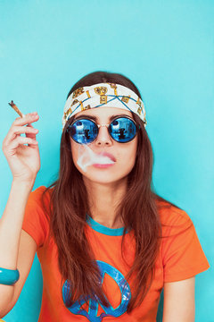 Boho girl portrait wearing blue sunglasses and smoking weed