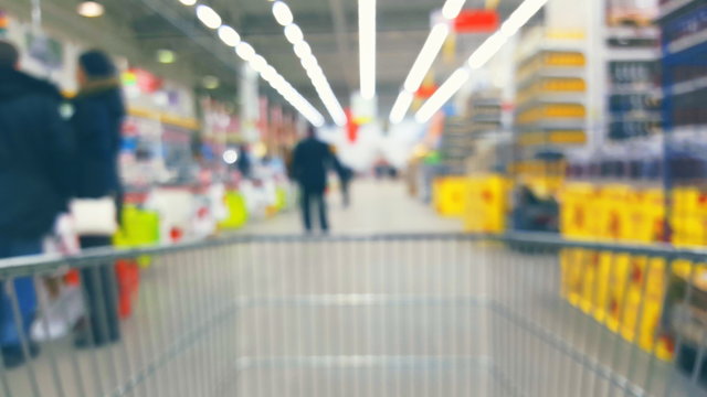 Supermarket interior with customers and trolley, blurred background