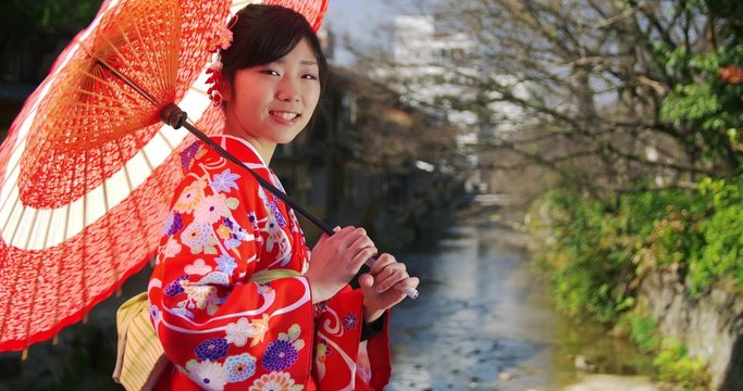 Beautiful Japanese girl in Kimono and parasol turns to the camera
