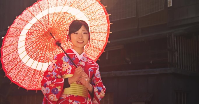 Beautiful young Japanese Girl wearing Kimono Spins old parasol