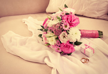 Wedding bouquet and bridesmaid dress on sofa in room