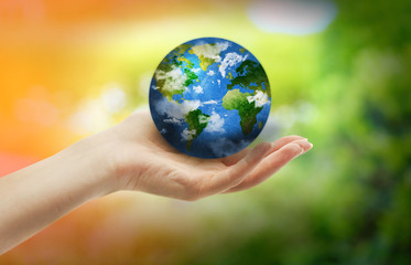 Woman holding globe on her hand on nature green background
