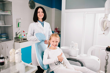Young handsome dentist treats tooth child, a woman dentist