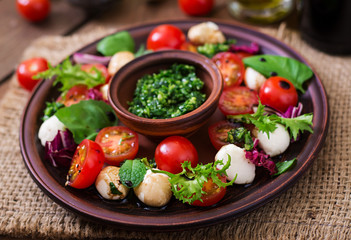 Caprese salad tomato and mozzarella with basil and herbs on a brown plate