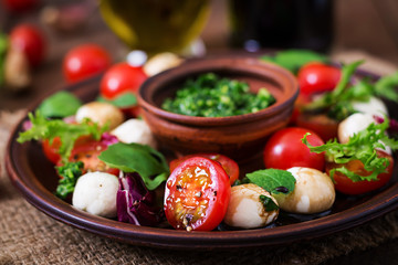 Caprese salad tomato and mozzarella with basil and herbs on a brown plate