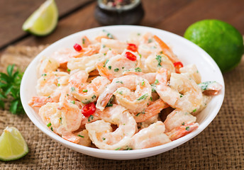 Shrimp in a creamy garlic sauce with parsley and lime in white bowl