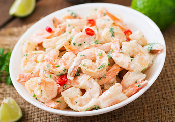 Shrimp in a creamy garlic sauce with parsley and lime in white bowl