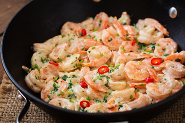 Shrimp in a creamy garlic sauce with parsley and lime in a frying pan