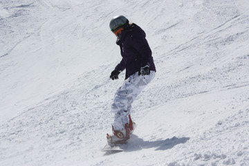 Fototapeta na wymiar Young snowboarder woman sliding downhill.