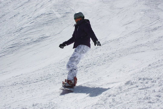 Young snowboarder woman sliding downhill.