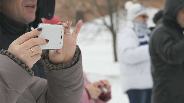 Woman takes sports on a white phone in winter