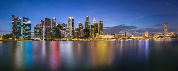 Obraz na płótnie Canvas Colorful Singapore business district skyline after sun set at Marina Bay. Panoramic image.