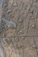 Drops of clear water on smoothed and polished wood surface.