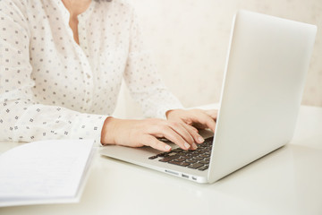 Portrait of a mature beautiful businesswomen enjoying, work on portable laptop computer, charming adult female using net-book while sitting in office or home interior.