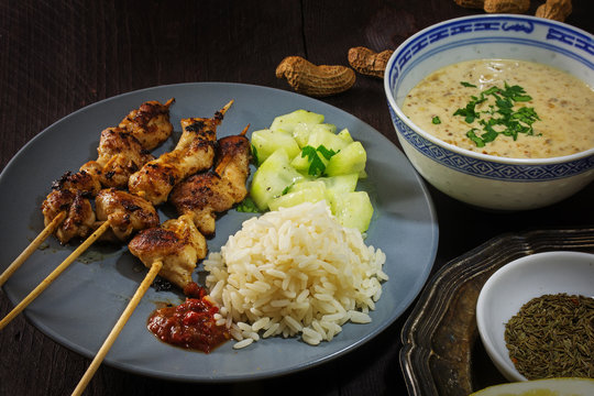 Asian satay meat skewers with rice, cucumber salad and peanut satay