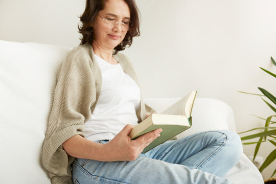 Charming mid age lady enjoying being at home and reading.