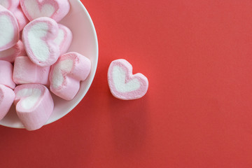 Pink heart shape marshmallows in white bowl flat lay