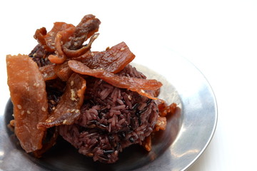 black sticky rice with fried sliced pork ,sesame , black pepper on metal dish