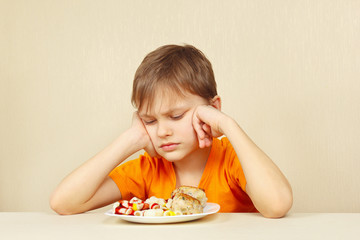 Little displeased boy does not want to eat a pasta with cutlet