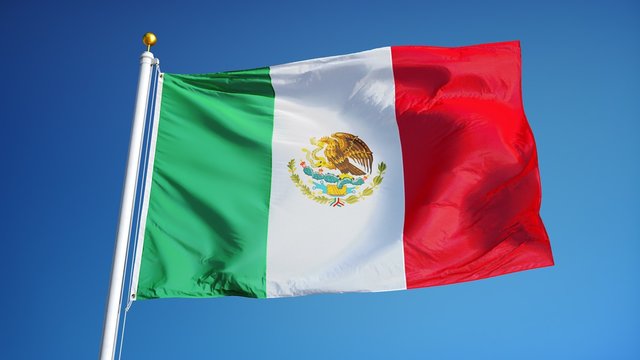Mexico flag waving in slow motion against clean blue sky, seamlessly looped, close up, isolated on alpha channel with black and white luminance matte, perfect for film, news, digital composition