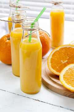 Natural and fresh orange juice in small bottles with fresh orange