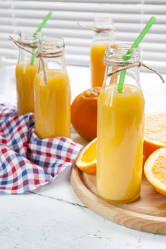 Natural and fresh orange juice in small bottles with fresh orange