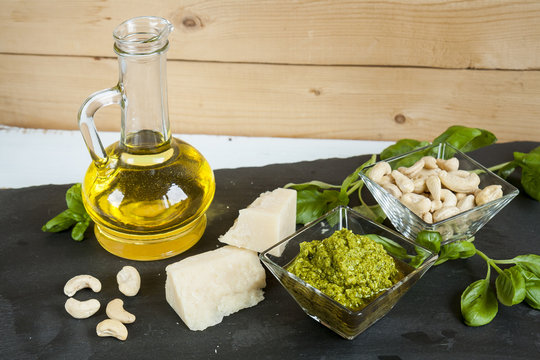Basil pesto fresh basil leaves parmigiano cheese olive oil and cashew seeds on black stone background