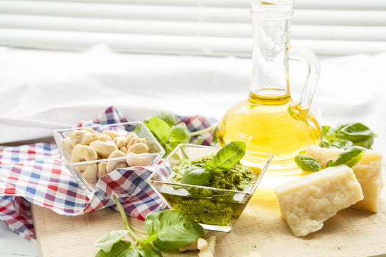 Basil pesto fresh basil leaves parmigiano cheese olive oil and cashew seeds on light wooden background