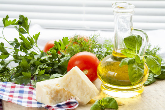 Parmigiano cheese, olive oil herbs and tomatoes on wooden background