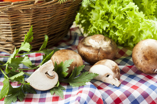 Mushrooms champignon vibrant green lettuce parsley from the market with basket on napkun