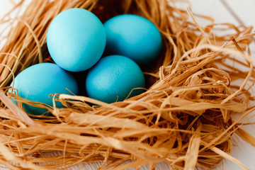 Obraz na płótnie Canvas blue Easter eggs in nest on white wooden background