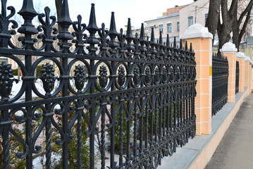 Black painted iron fence mounted at  small wall of brickstones 