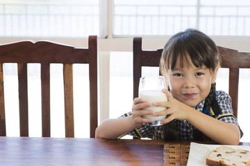 a school uniform little girl is drinking milk