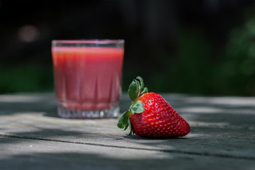 One strawberry on wooden table with vitamin drik