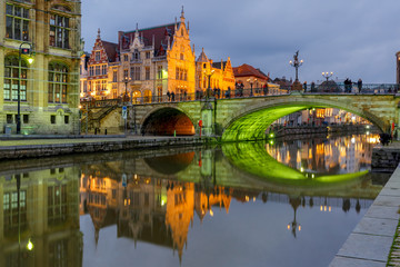 Picturesque medieval building and St. Michael's Bridge with an unusual green illumination in the evening in Ghent, Belgium