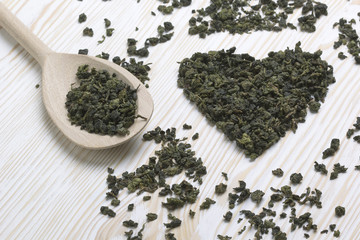 Green tea leaf in shape heart , spoon on  wooden  background