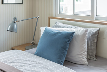blue pillow on single bed with modern grey lamp in modern bedroo