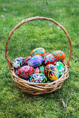 colored easter eggs in basket on spring grass