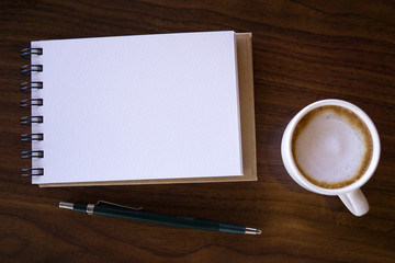 Open a blank white notebook with hot coffee on table