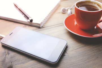 phone, earphone, coffee, notebook and pen on table