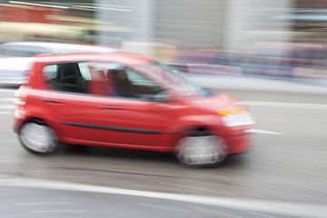Fototapeta na wymiar Red car in motion blur, car driving fast in city