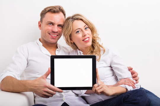 Couple holding blank screen tablet
