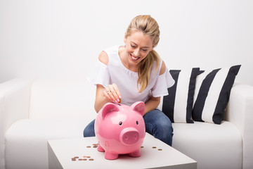 Woman putting coins in pink piggy bank