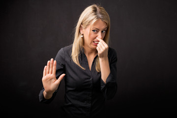 Woman holding her nose in disgust and holding her hand out