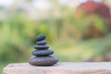 Obraz na płótnie Canvas Zen stones on wood table with garden blurred background.