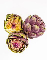 Three fresh purple artichokes, isolated on white background.