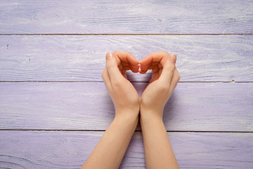 Hand make a heart on a wooden background with copy space for your text