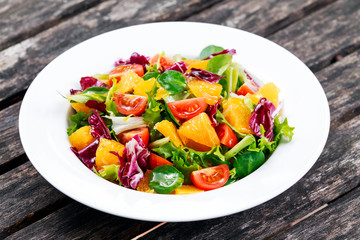 Fresh Orange, vegetables salad on wooden table.