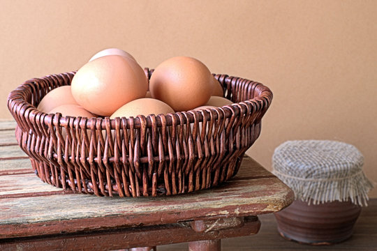 Eggs.   Basket with eggs and ceramic pot on old wooden table.
 