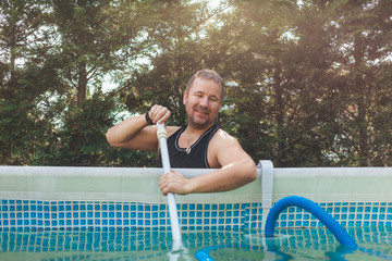 Man smiles and cleaning the swimming pool